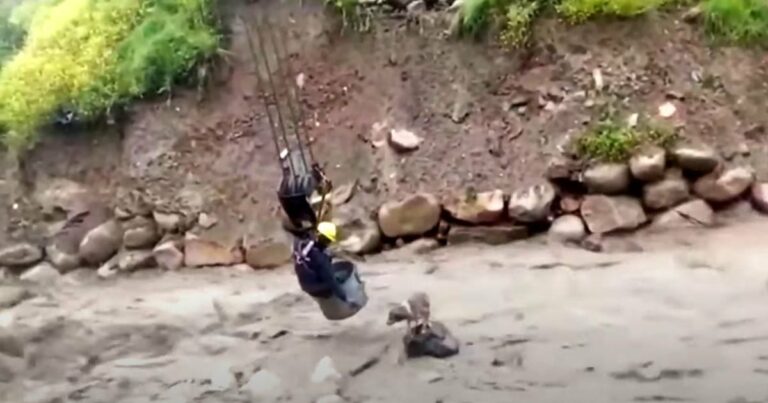 Építőipari munkás bemászik a daru vödrébe és kilendül a folyó fölé, hogy segítsen az elveszett kutyának